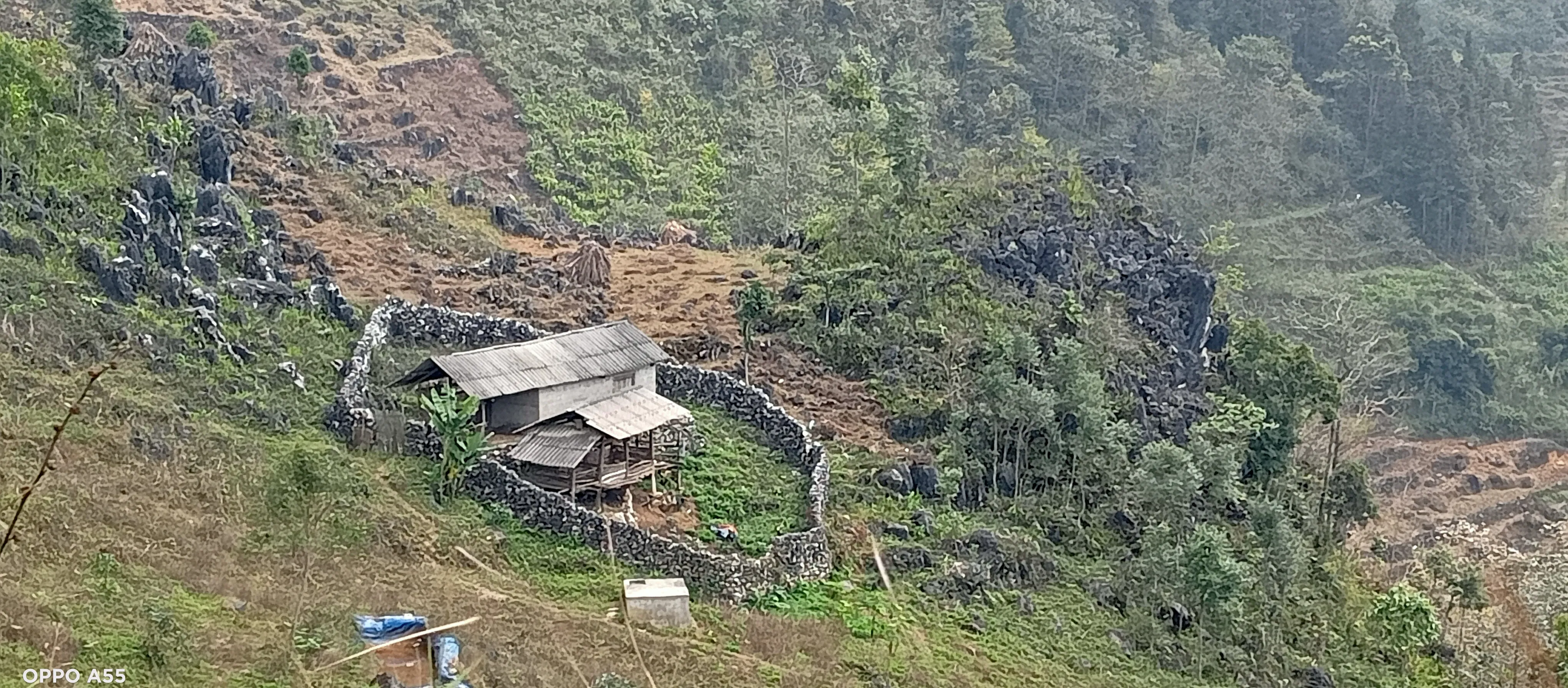 A traditional homestead enclosed by a hand-built dry-stone wall on a karst hillside in the Dong Van region.