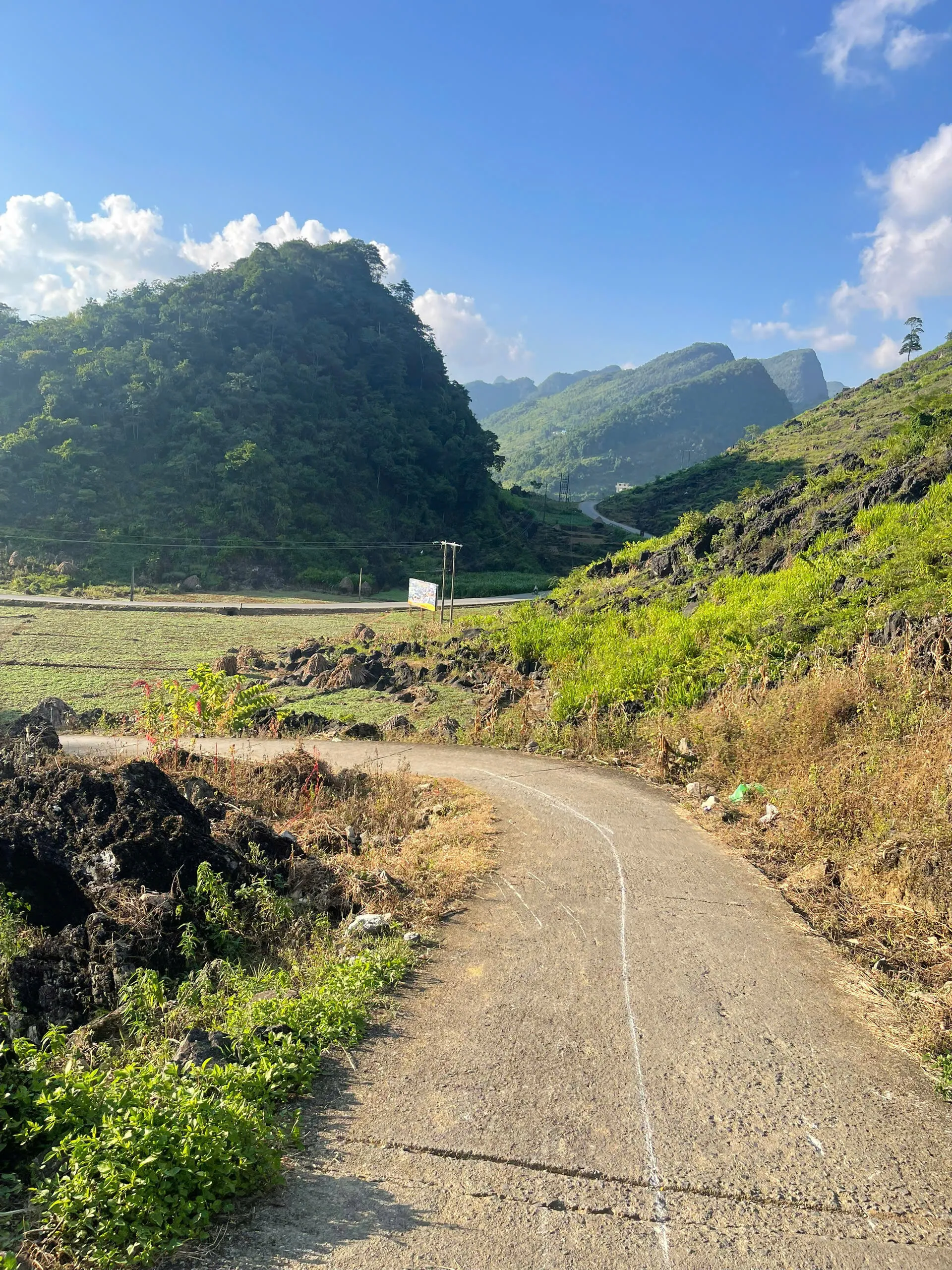Concrete and stone village path through eastern Ha Giang karst farmland.