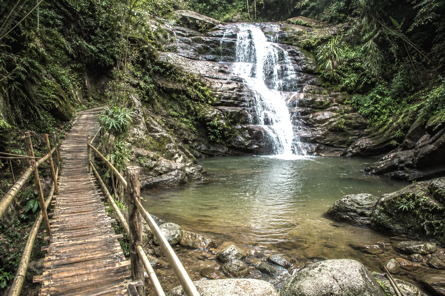 Lower waterfall and community footbridge on the Du Gia river path