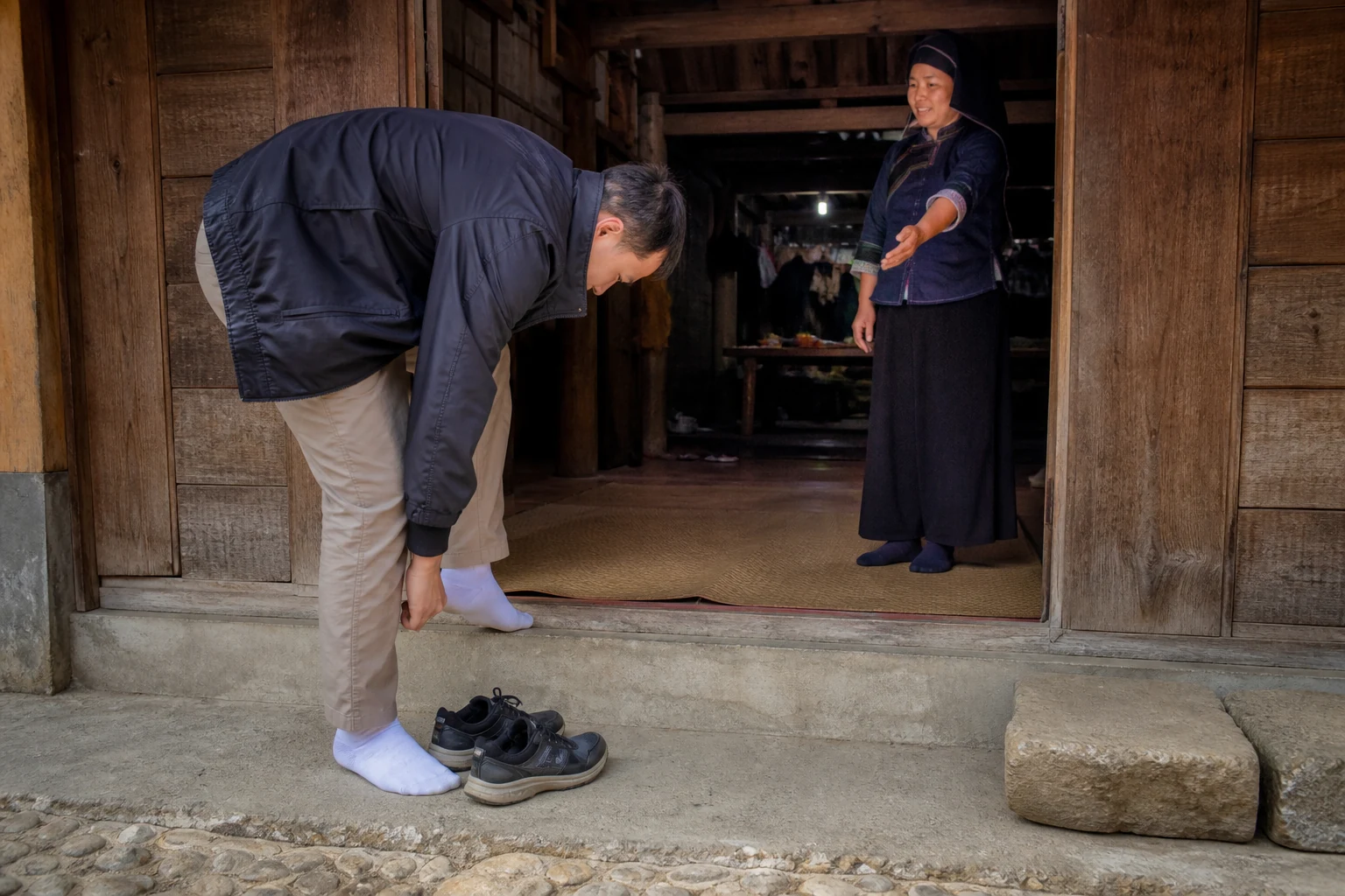 Guest removing hiking boots on a wooden threshold before entering a homestay