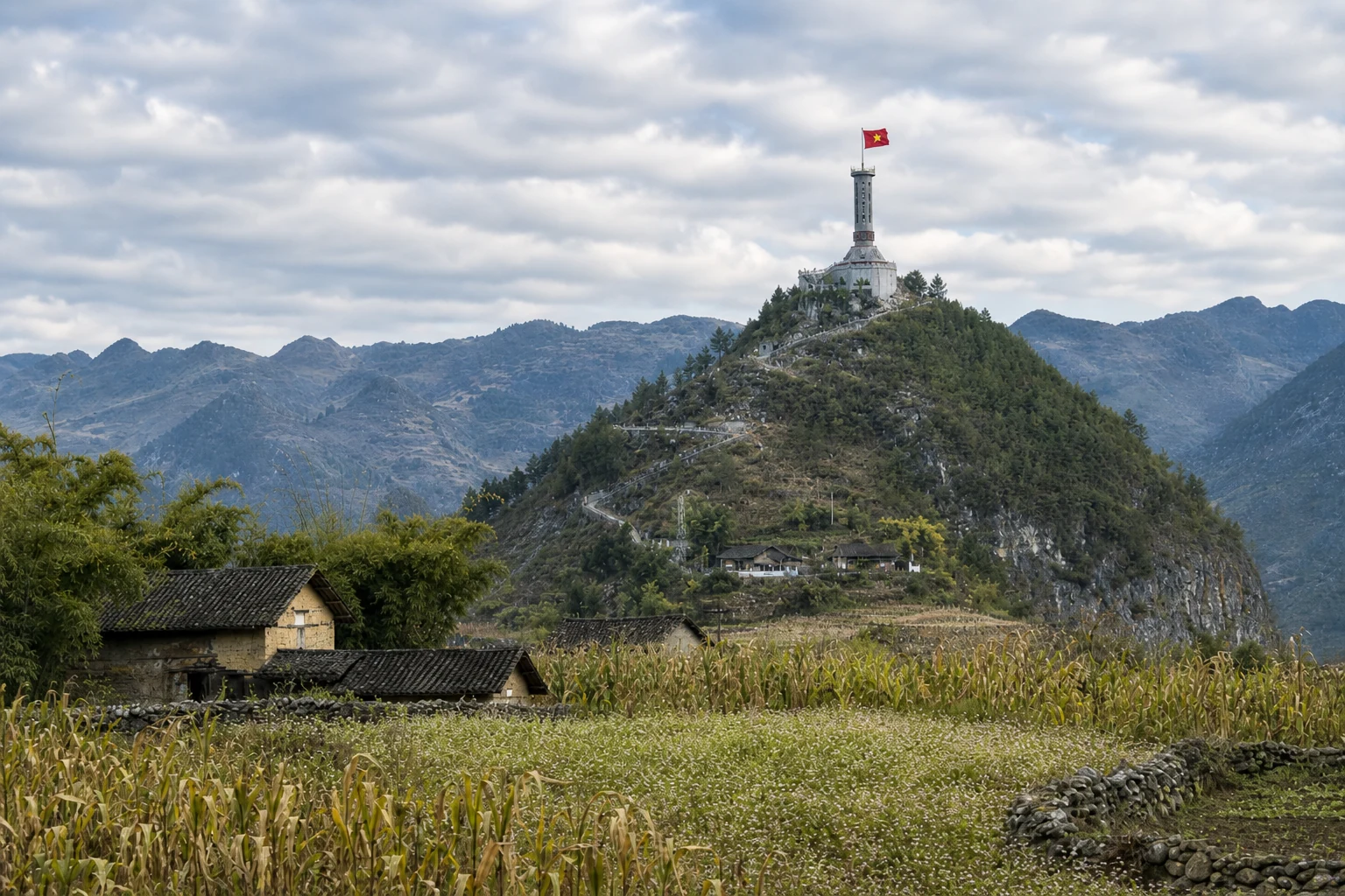 Lung Cu Flag Tower above cultivated plateau fields and stone-walled farmland