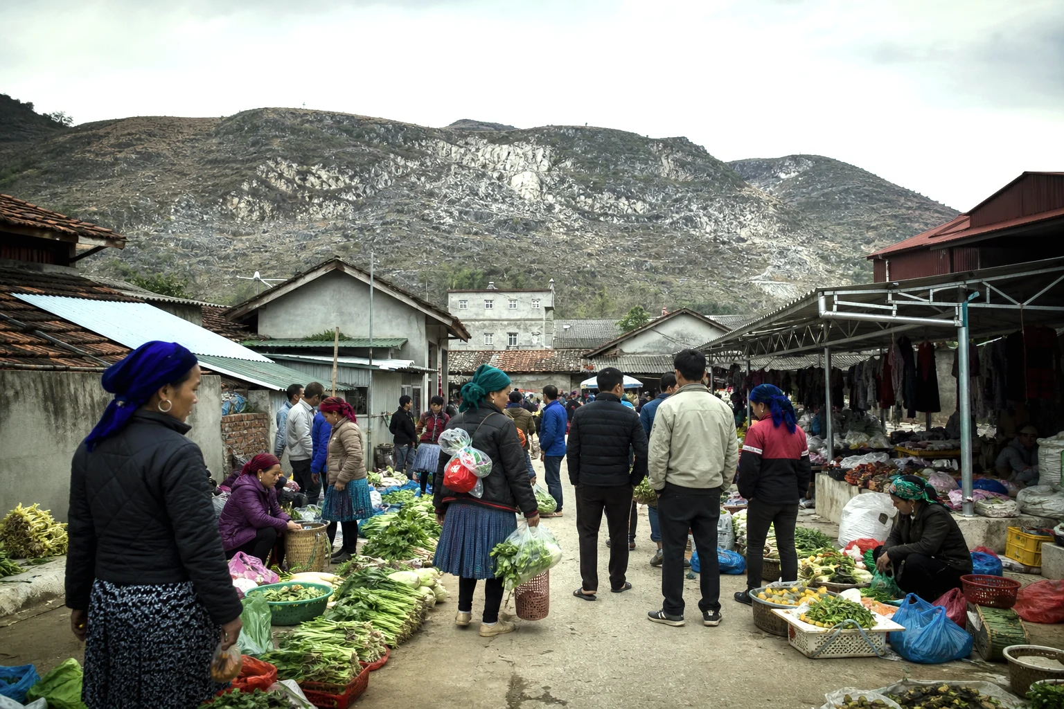 Market shoppers and produce stalls beneath limestone slopes in Meo Vac