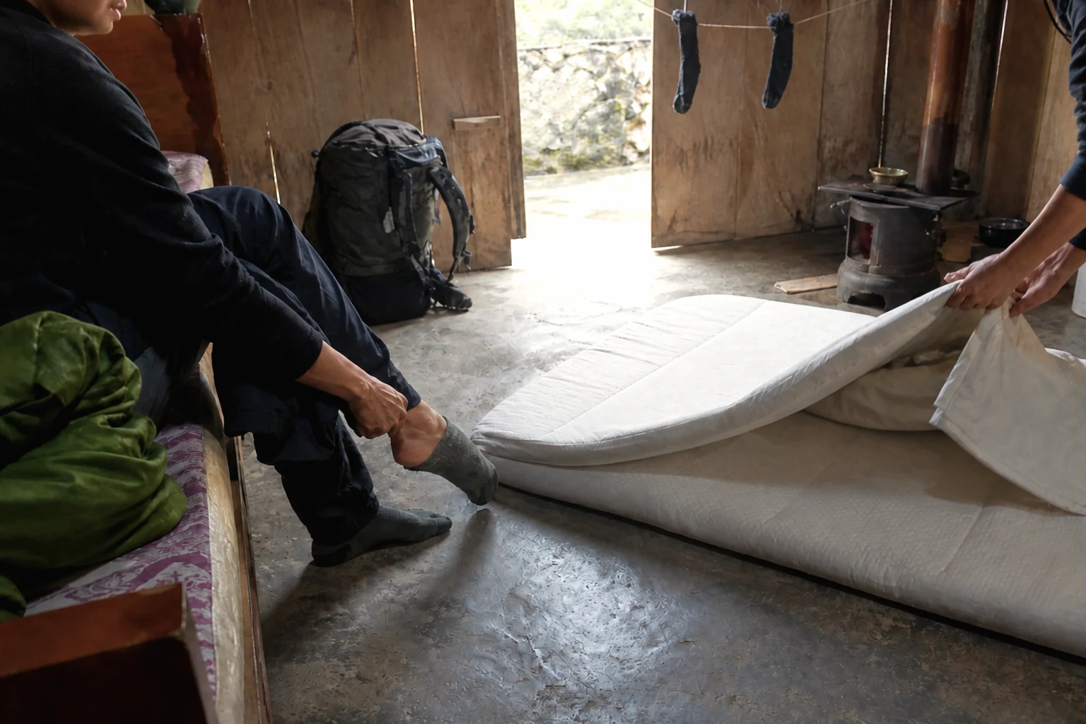 Trekkers resting and laying out bedding in a simple White Hmong homestay room