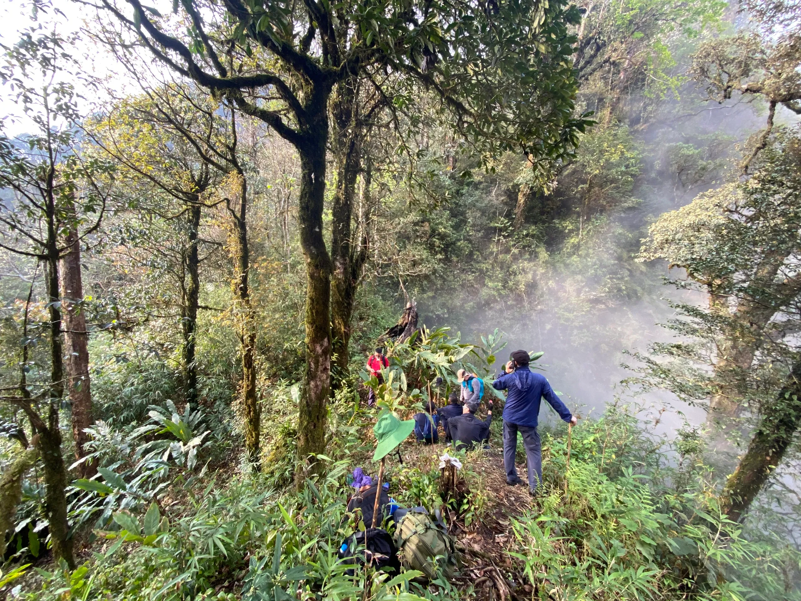 Trekkers walk a foggy ridge section on Tay Con Linh.