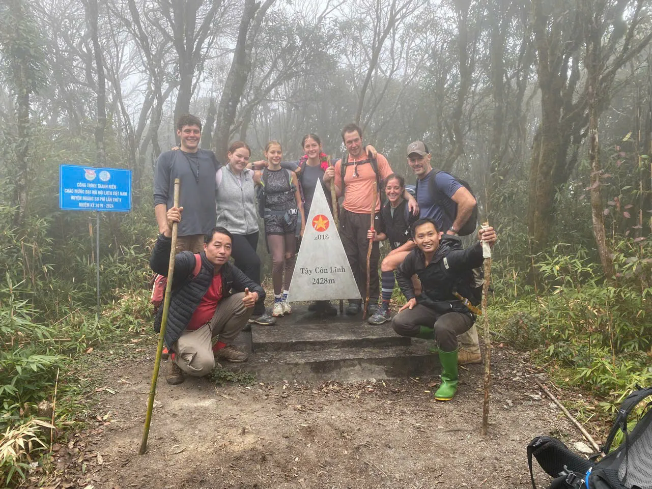 Trekking group at the Tay Con Linh summit marker when conditions allow